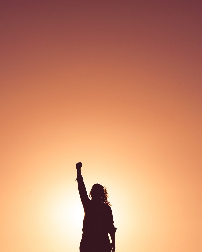 silhouette of a woman against an orange sky