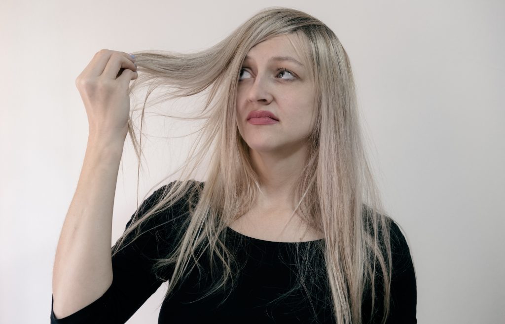 a woman grimacing at her lank hair