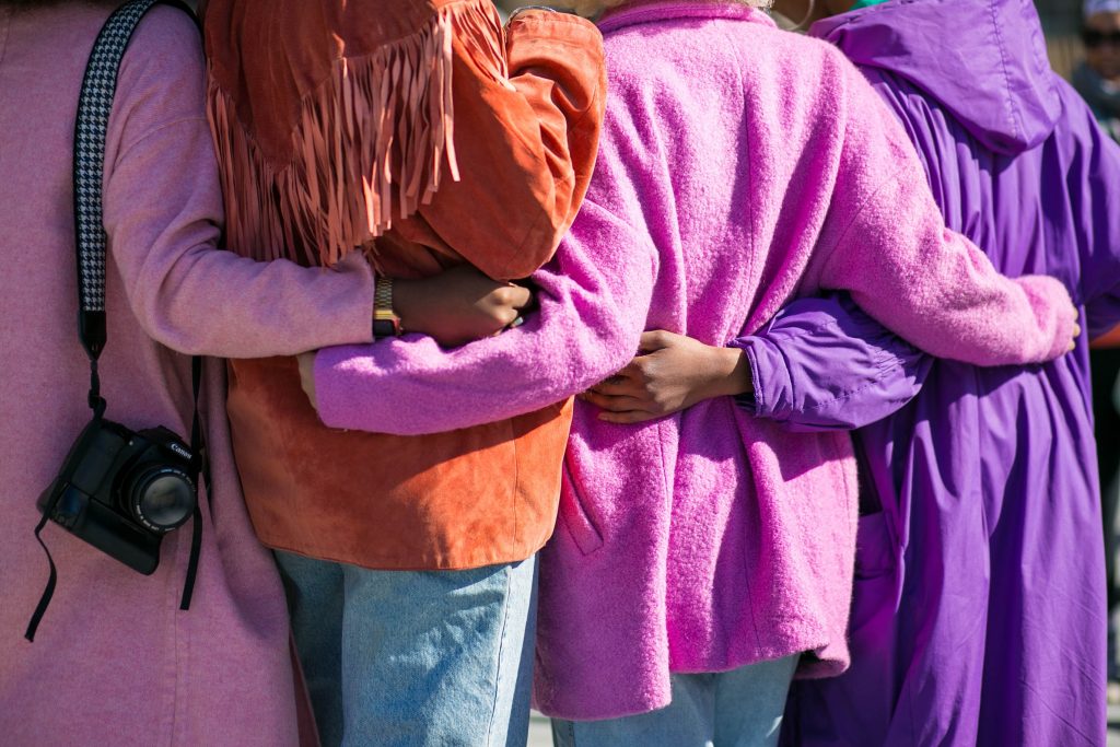 woman wearing pink and purple coats hugging each other