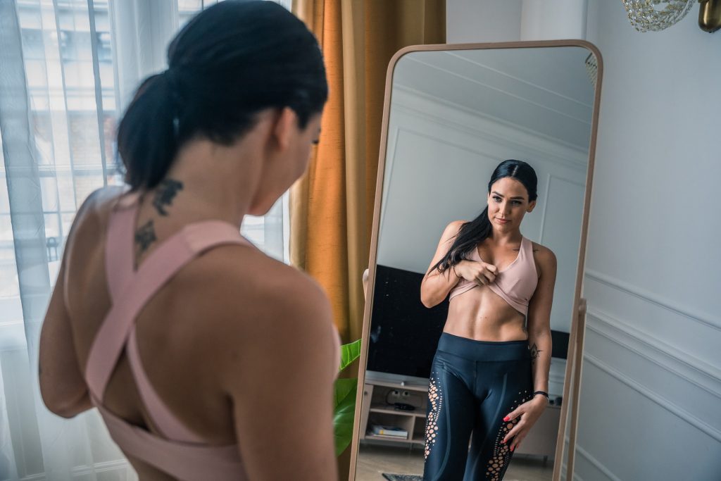 a woman looking at her abs in the mirror