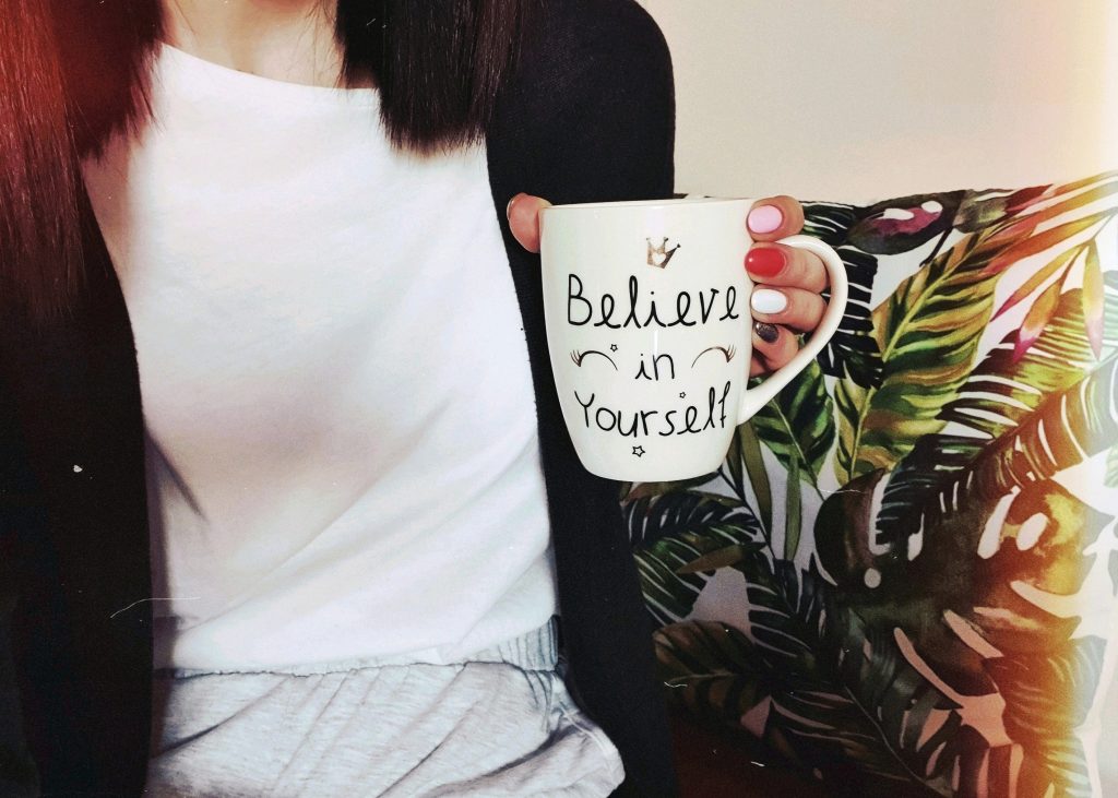 a woman holding a mug that says 'believe in yourself'