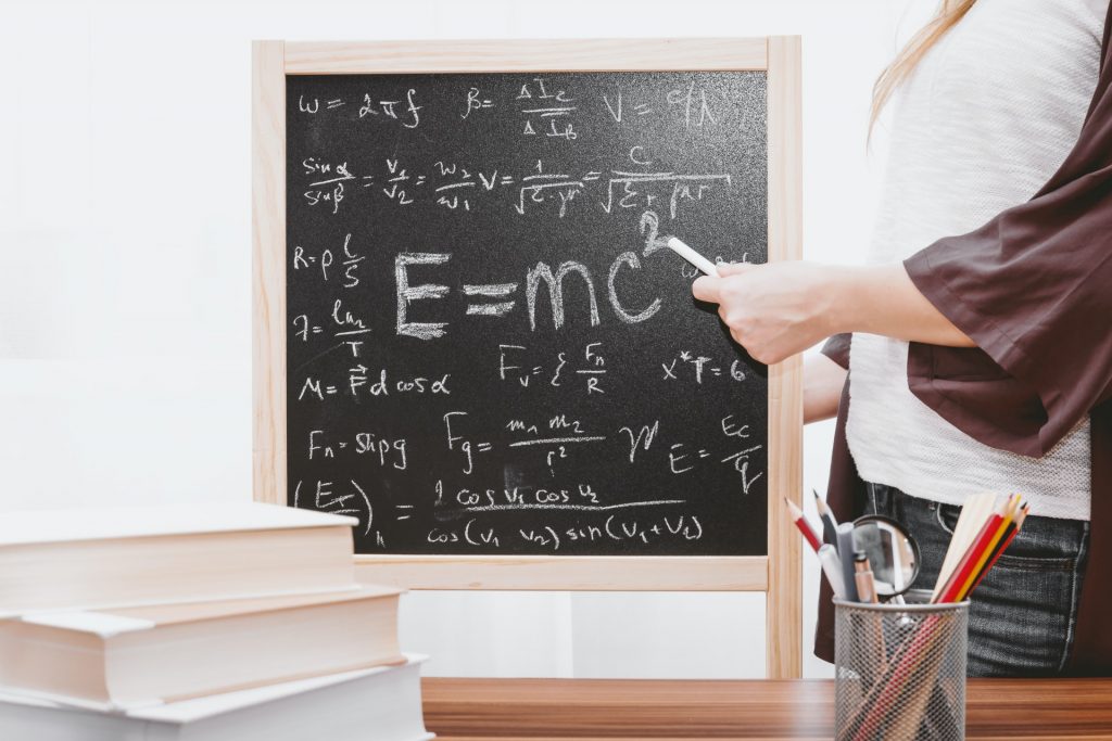 a woman and a blackboard with algebra on it