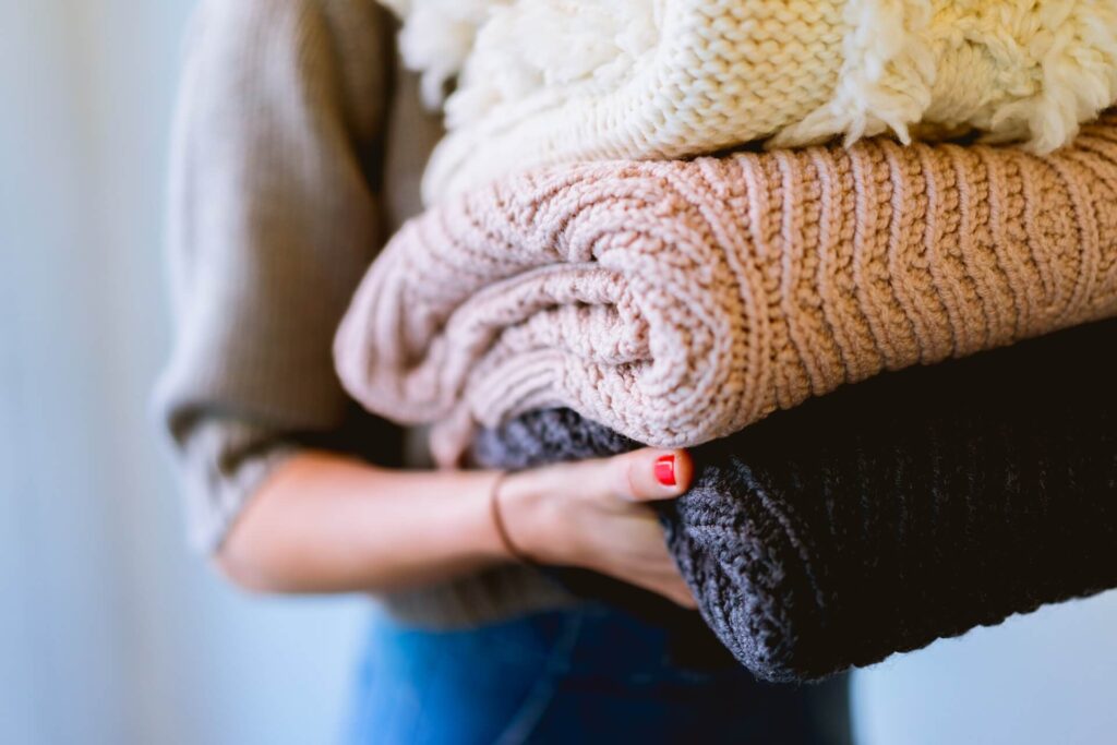 a woman holding some cardigans