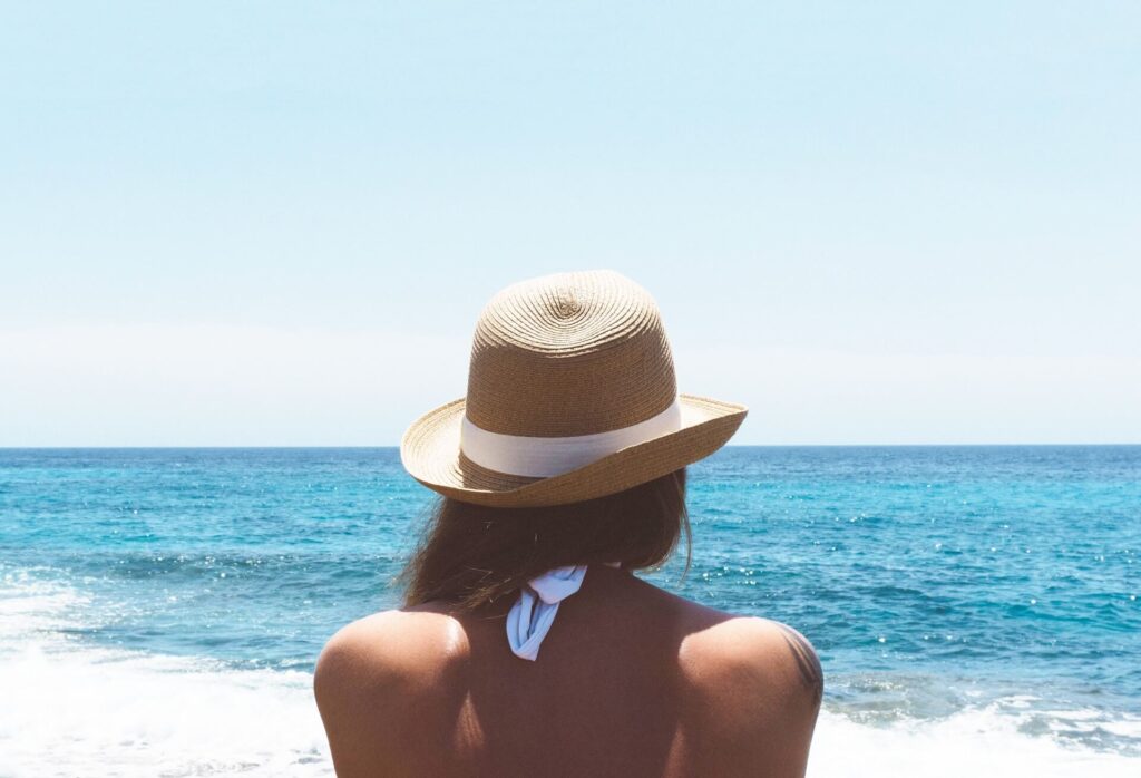 a girl facing the sea wearing a straw hat