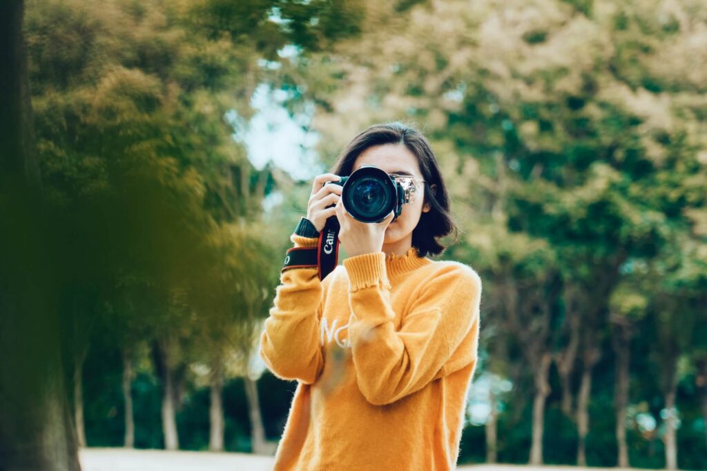 a woman in a forest with a dslr camera